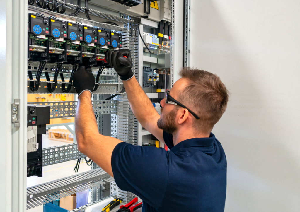 électricien portant des gants et des lunettes de protection se tenant debout face à un compteur électrique